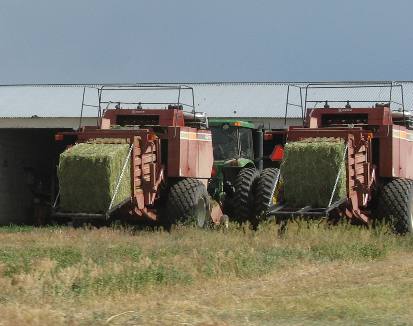 Two hay bailing machines about to "birth" a big bale of hay