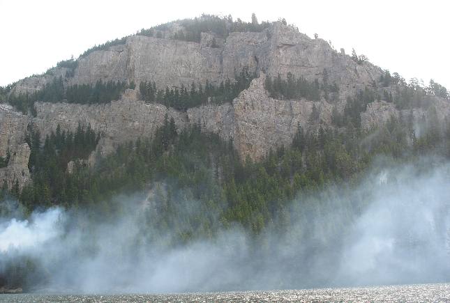 Horizontally layered limestone bluff visible above smoke from Meriwether Fire