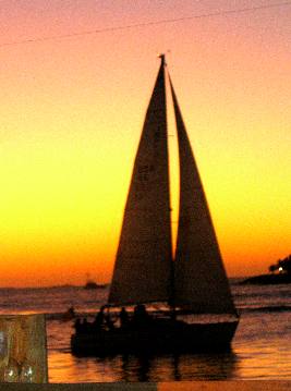 Private sail boat passing by Mallory Square and Sunset Pier after a spectacular sunset