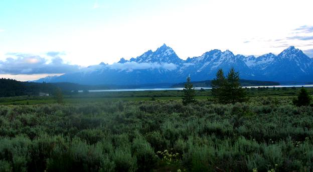 Grand Teton Mountain towering above the clouds and silouetted against an evening sky in Grand Teton National Park
