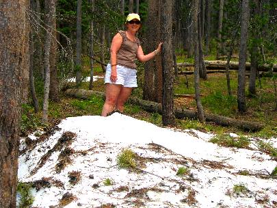 Joyce Hendrix standing behind a patch of snow in Yellowstone National Park in her shorts