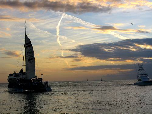 One of the Fury fleets catamarans sailing past Mallory Square on a sunset cruise