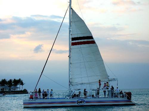 A Fury catamaran out on a sunset cruise is passing Sunset Key
