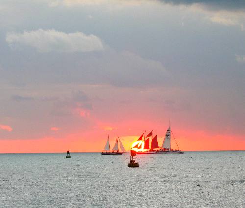 Fabulous Key West Sunset with three sunset cruise sailboats, the schooner Appledore on the left, the schooner Jolly II Rover in the center with red sails and one of the Fury catamarans on the right with the stripes in it's sail