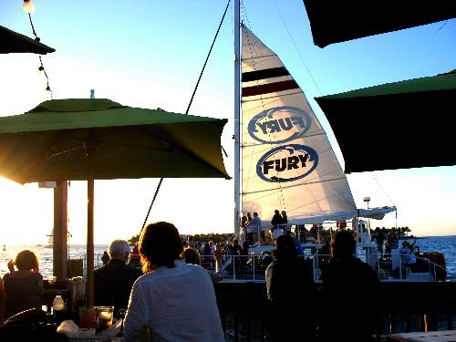 Fury sail viewed between brightly colored umbrellas on Sunset Pier
