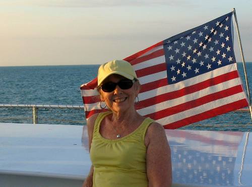 Joyce posing with the US Flag flying on the Party Cat Sunset Cruise