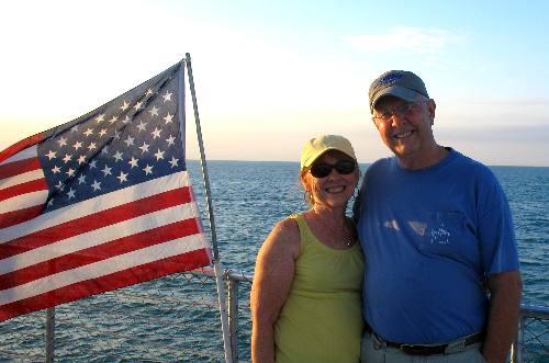 Joyce and Mike posing with the US Flag flying on the Party Cat Sunset Cruise out of Key West, Florida