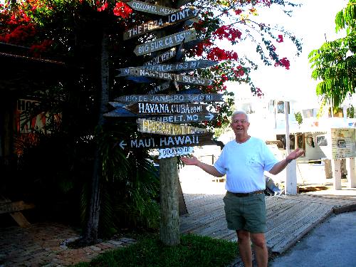 Mike with mile post and direction markers outside Hogfish Grill in Key West