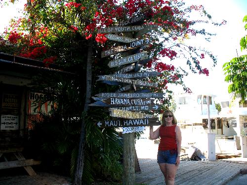 Joyce posing with the milepost - direction marker outside Hogfish Grill on Stock Island